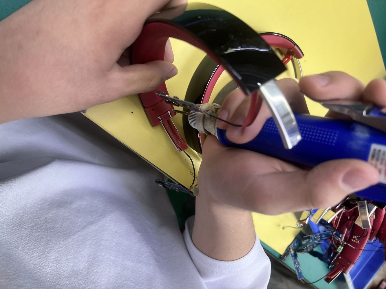 Worker inspecting Bluetooth headphone headband and metal hinge parts